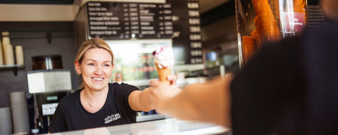Eismacherin übergibt hausgemachtes Eis an Kunden im Eiscafé Hoffmann am Dümmer-See.