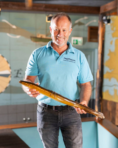 Marc von Aal Hoffmann präsentiert einen Aal und erklärt die Reise der Aale während einer Räuchereiführung.