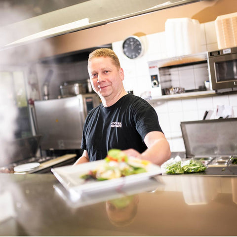 Mann kocht in der offenen Küche des Fischhauses Hoffmann am Dümmer-See.